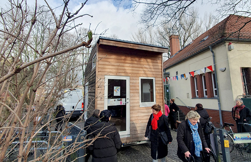 Kolleginnen und Besucherinnen haben das TinyHaus durch das Tor vorbei an dem Bäumchen geschoben.